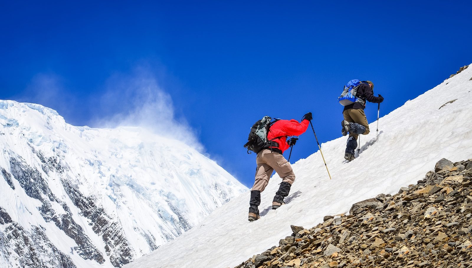 Two Mountain Trekkers On Snow With Peaks Background Two mountain backpackers walking on snow with peaks background Himalayas